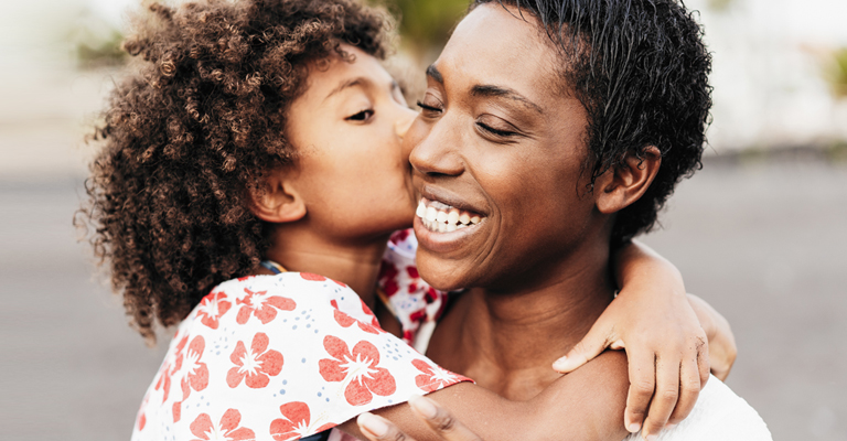 Happy black mother having tender moment with her child at the beach summer day - Focus on mother face